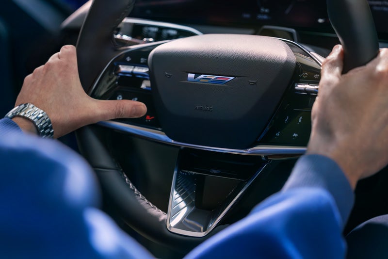Close-up of a Man About to Press the V-Button on the 2026 OPTIQ-V Steering Wheel | Huston Cadillac in LAKE WALES FL