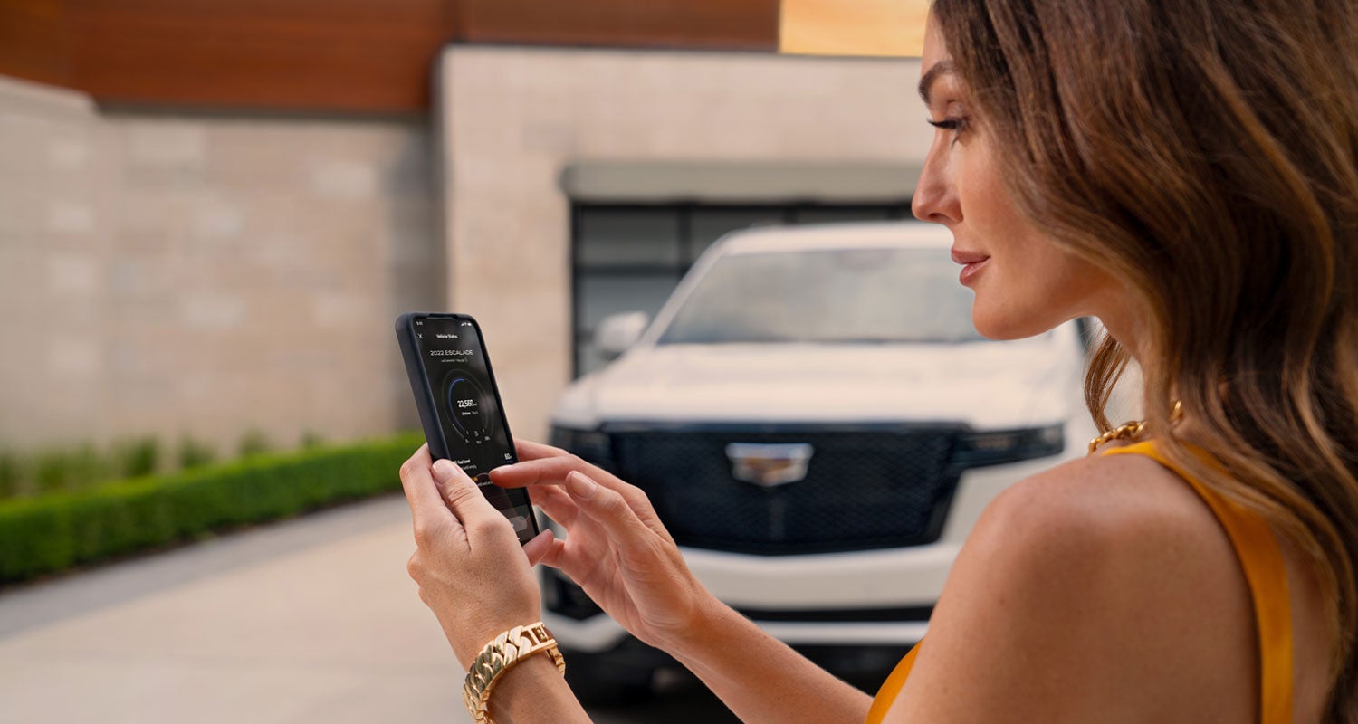 lady checking her mobile with a Cadillac vehicle background | Huston Cadillac in LAKE WALES FL